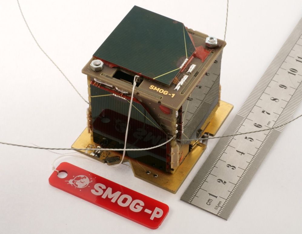 The square SMOG-P satellite shown alongside a ruler showing that the satellite measures six inches on each side.
