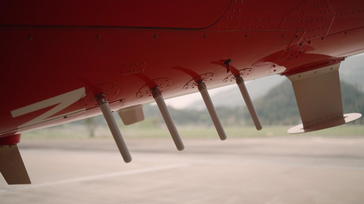 Four antennas are mounted on the underside of a red helicopter.