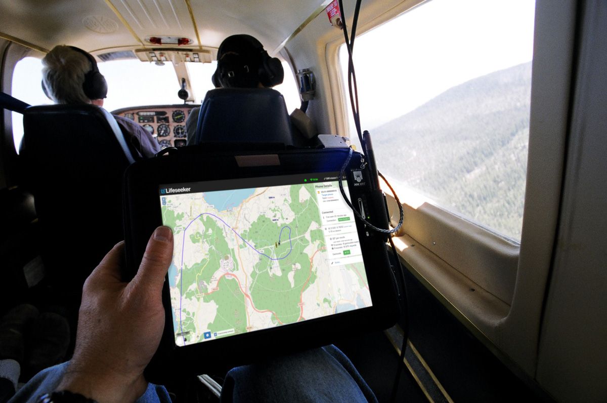 A tablet showing the Lifeseeker interface with a map and location information being held inside a helicopter.