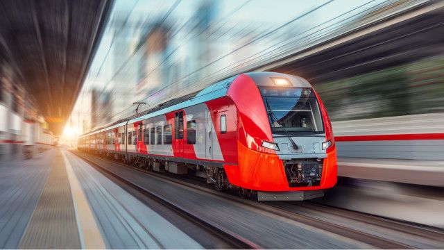An electric passenger train driving at high speed among urban landscape